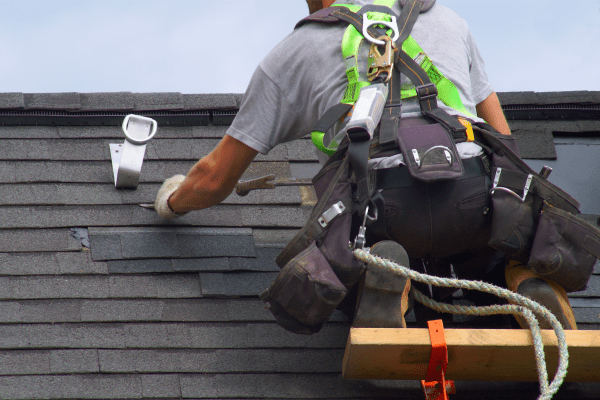 worker on a roof inspecting shingles. Getting Your Roof Replaced? Here's What You Need To Know And Expect!